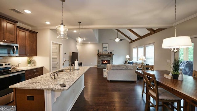 kitchen featuring sink, stainless steel appliances, hanging light fixtures, and a kitchen bar