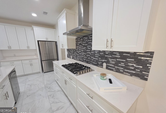 kitchen featuring white cabinetry, wall chimney range hood, backsplash, and stainless steel appliances