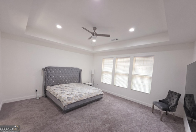 carpeted bedroom featuring ceiling fan and a tray ceiling