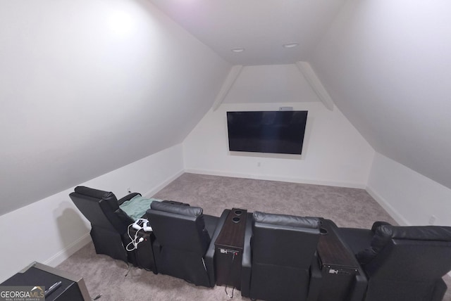 carpeted home theater room with vaulted ceiling