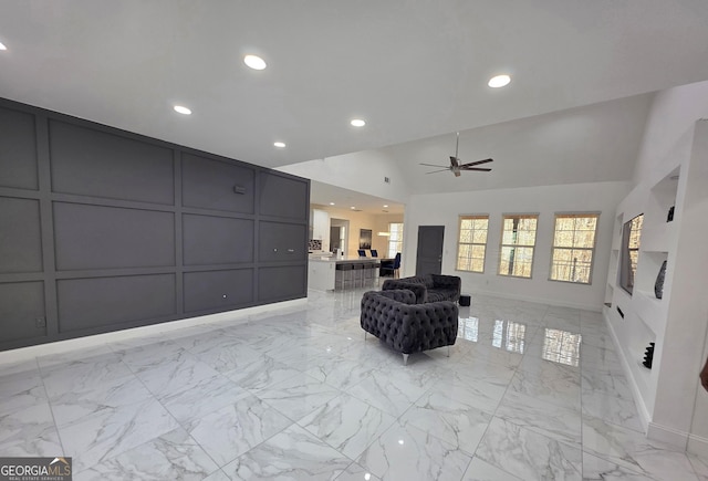 sitting room with ceiling fan and high vaulted ceiling