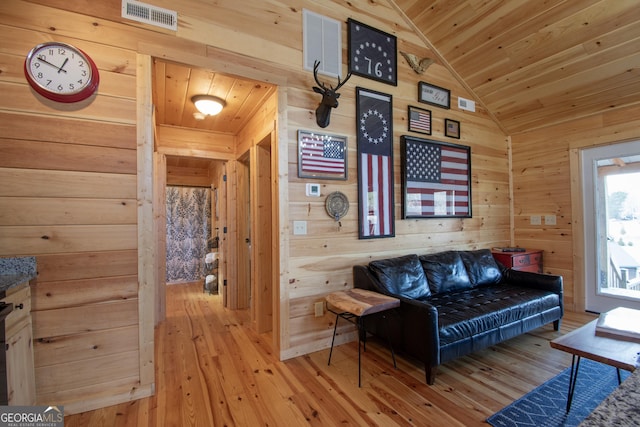 living room with lofted ceiling, light wood-type flooring, wooden ceiling, and wooden walls