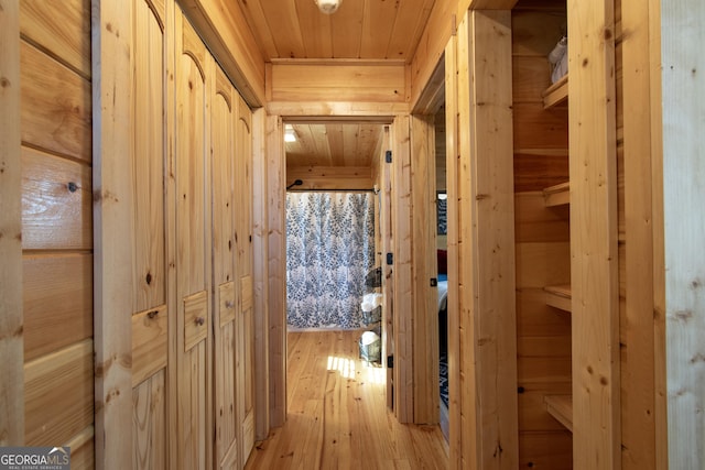 hall with wood ceiling, wooden walls, and light wood-type flooring