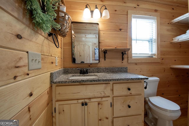 bathroom with vanity, wooden walls, and toilet