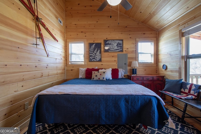 bedroom with ceiling fan, lofted ceiling, wood ceiling, and wood walls