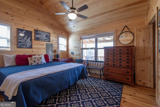 bedroom with lofted ceiling, hardwood / wood-style floors, multiple windows, and wood walls