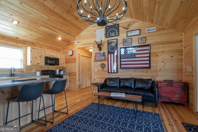 living room with lofted ceiling, sink, wooden ceiling, wooden walls, and light hardwood / wood-style floors