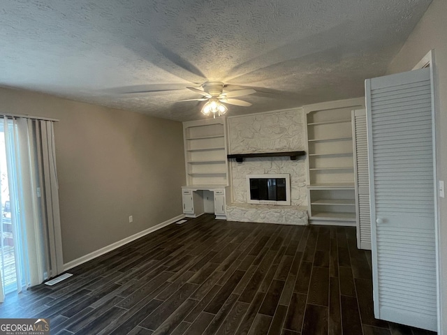 unfurnished living room featuring dark wood-type flooring, a fireplace, a textured ceiling, and a wealth of natural light