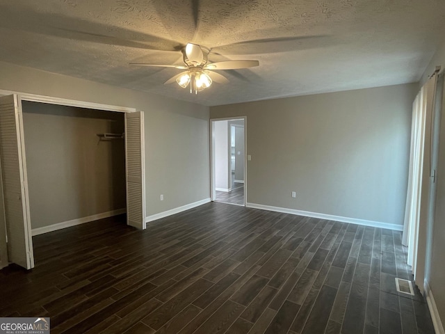 unfurnished bedroom with ceiling fan, a closet, dark hardwood / wood-style floors, and a textured ceiling