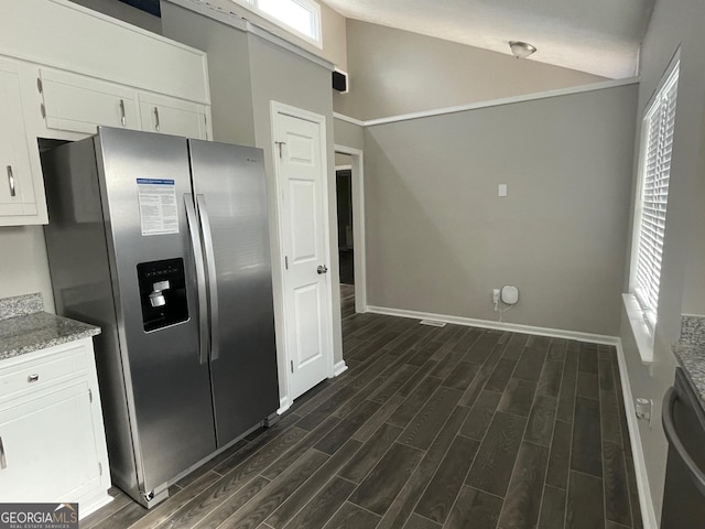 kitchen with light stone counters, vaulted ceiling, stainless steel appliances, and white cabinets