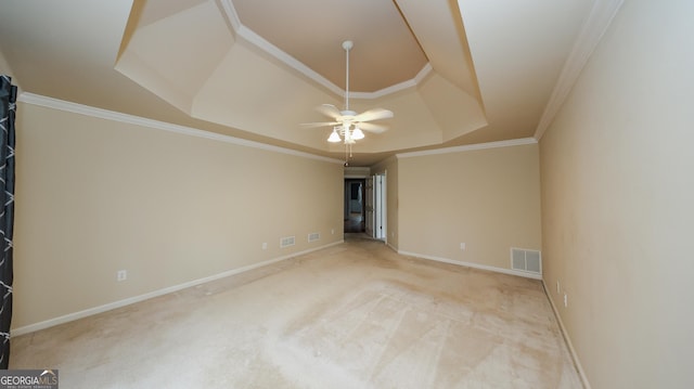 carpeted spare room featuring a tray ceiling, crown molding, visible vents, and baseboards