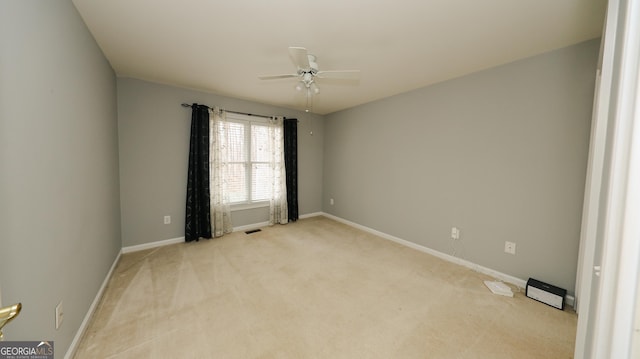 spare room featuring visible vents, light colored carpet, baseboards, and a ceiling fan