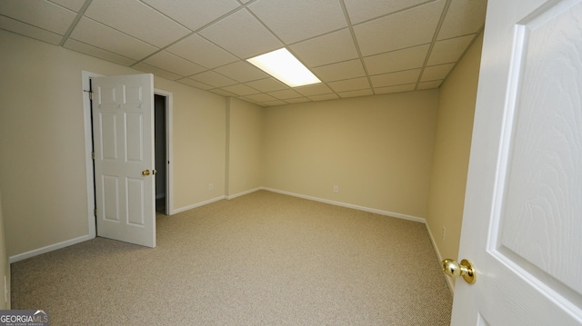 spare room featuring carpet flooring, baseboards, and a drop ceiling