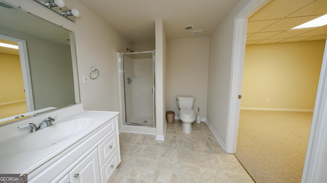 bathroom featuring a shower stall, baseboards, toilet, vanity, and a paneled ceiling