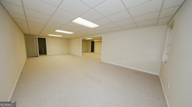 finished basement with a drop ceiling, baseboards, and carpet