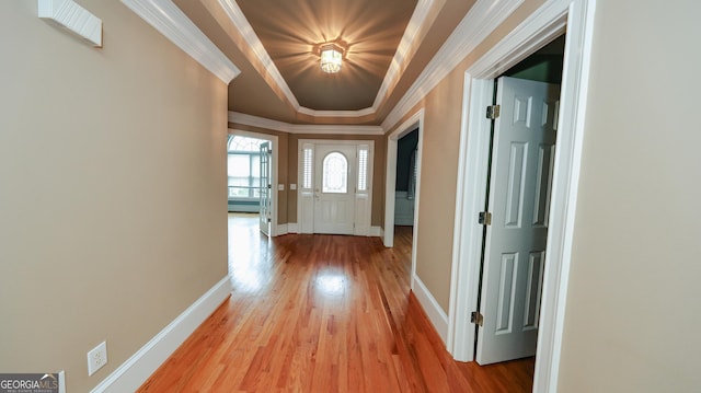 doorway featuring a tray ceiling, light wood-type flooring, baseboards, and crown molding