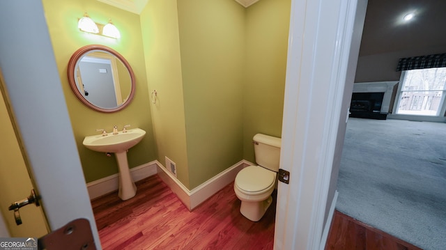 half bathroom featuring visible vents, toilet, baseboards, and wood finished floors