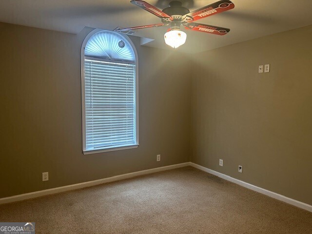 unfurnished room featuring ceiling fan and carpet flooring