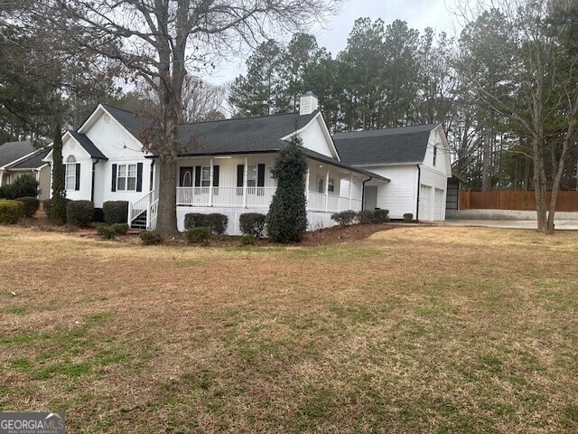 view of front facade with a porch, a garage, and a front lawn