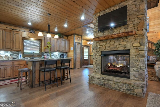 kitchen with dark wood-type flooring, wood ceiling, decorative light fixtures, and a breakfast bar