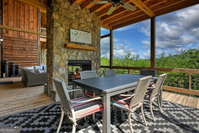 sunroom with beam ceiling, ceiling fan, and an outdoor stone fireplace