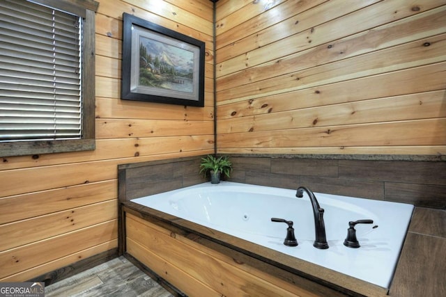 bathroom with wood-type flooring, a washtub, and wooden walls