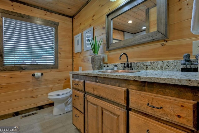 bathroom featuring vanity, wooden walls, wooden ceiling, and toilet