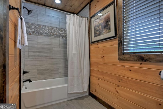 bathroom featuring shower / bathtub combination with curtain and wooden walls