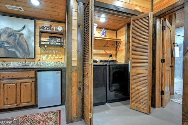 washroom with washer and dryer, indoor wet bar, wooden ceiling, and wooden walls