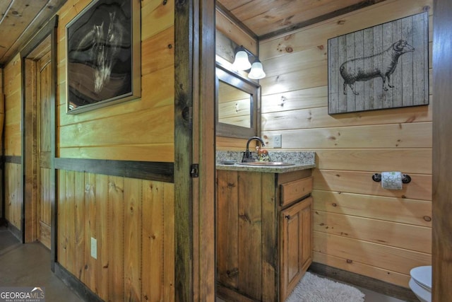 bathroom featuring vanity, toilet, and wood walls