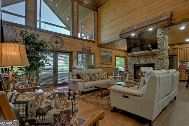 living room with wood ceiling, a towering ceiling, wooden walls, a fireplace, and light wood-type flooring