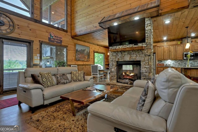 living room with wood walls, wood ceiling, hardwood / wood-style flooring, a towering ceiling, and a fireplace