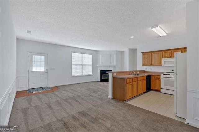 kitchen featuring light carpet, white appliances, kitchen peninsula, and a textured ceiling