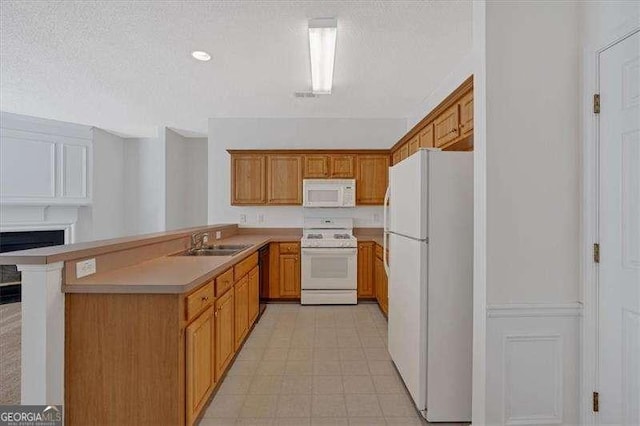 kitchen with white appliances, kitchen peninsula, sink, and a textured ceiling