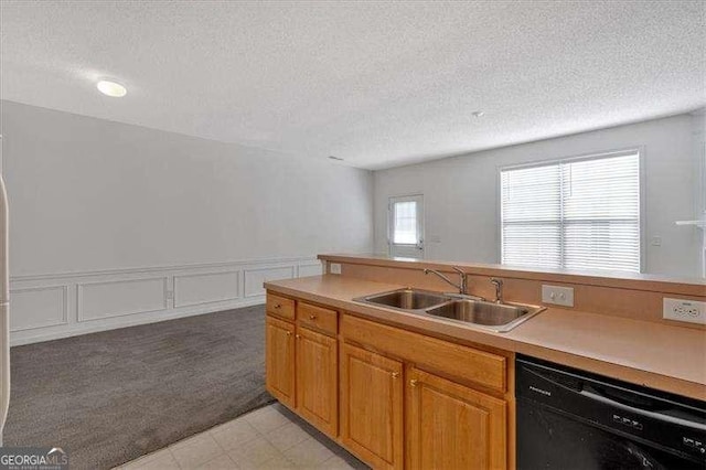 kitchen with black dishwasher, sink, and a textured ceiling