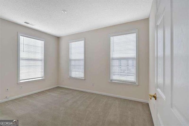 unfurnished room featuring light carpet and a textured ceiling