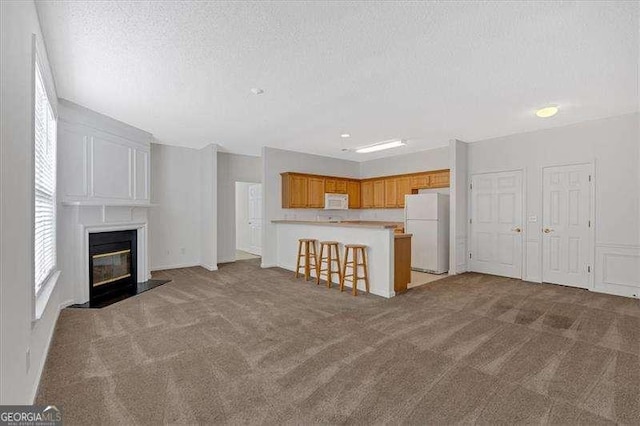 unfurnished living room with a fireplace, light colored carpet, and a textured ceiling