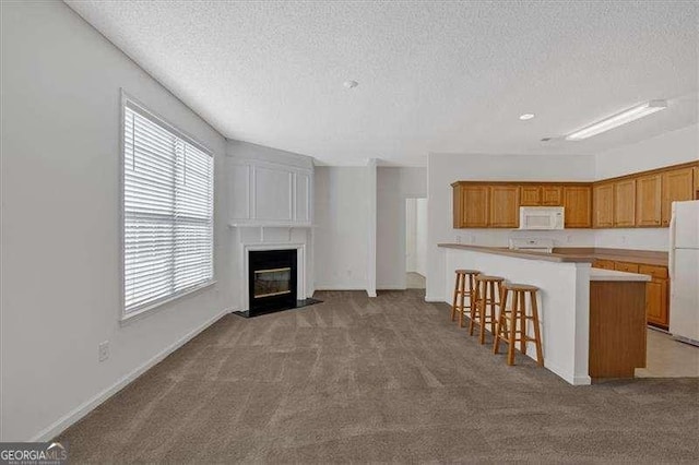 unfurnished living room with light carpet, a textured ceiling, and a fireplace