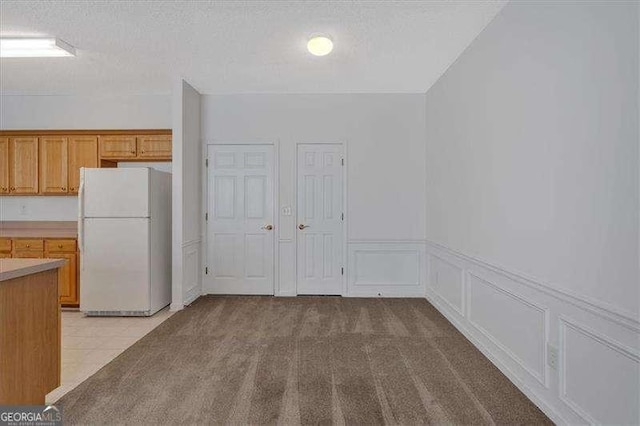 kitchen featuring light carpet, a textured ceiling, and white fridge