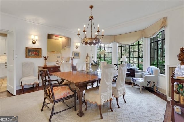 dining room featuring ornamental molding, light hardwood / wood-style flooring, and a notable chandelier