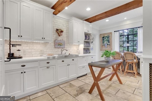 kitchen featuring backsplash, beamed ceiling, and white cabinets