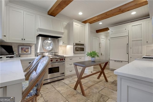 kitchen featuring white cabinetry, high quality appliances, wall chimney range hood, beam ceiling, and backsplash