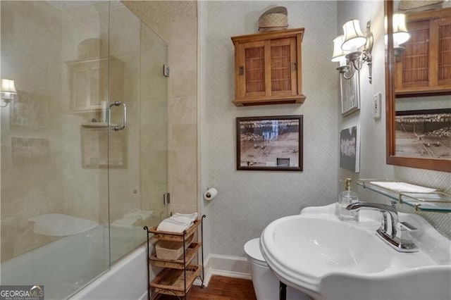 full bathroom with bath / shower combo with glass door, wood-type flooring, toilet, and sink