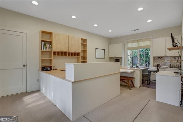 kitchen featuring backsplash, kitchen peninsula, and white cabinets