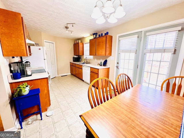 kitchen featuring an inviting chandelier, sink, white appliances, and a textured ceiling