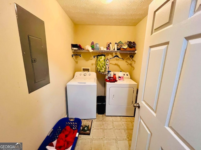 washroom featuring independent washer and dryer, electric panel, and a textured ceiling