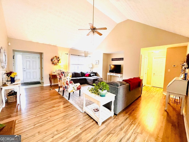 living room featuring ceiling fan, high vaulted ceiling, and light wood-type flooring