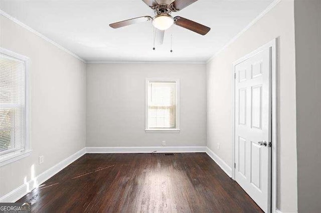 empty room with dark hardwood / wood-style flooring, ornamental molding, and ceiling fan