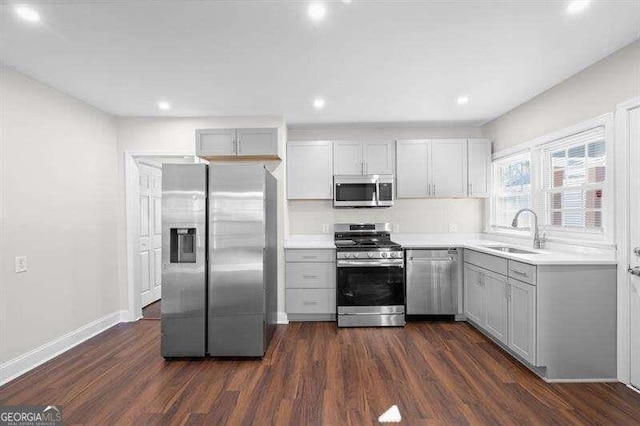 kitchen with dark wood-type flooring, appliances with stainless steel finishes, sink, and gray cabinetry