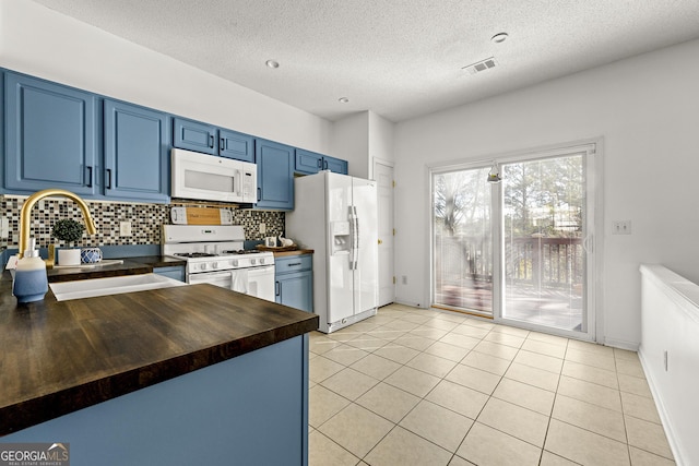 kitchen featuring light tile patterned flooring, white appliances, a sink, wooden counters, and blue cabinetry